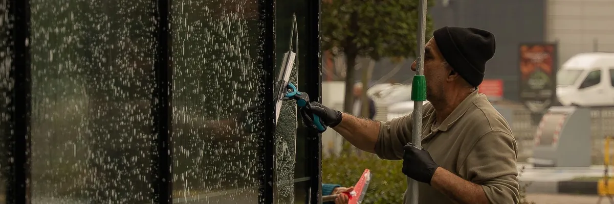 Window cleaner using a squeegee pole on a glass building front